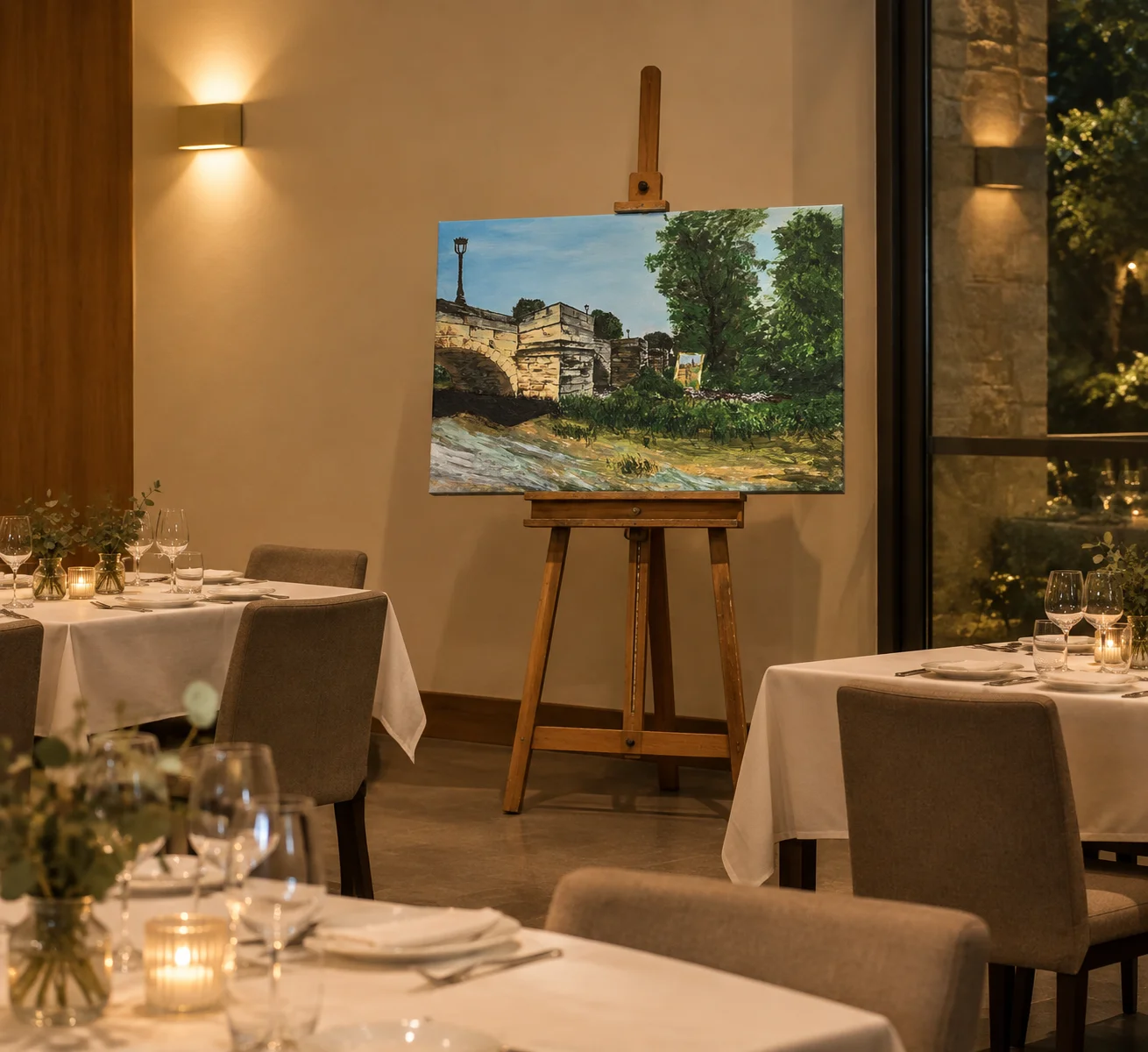 Puente de Santa María, a finished landscape painting on an easel in a restaurant setting
