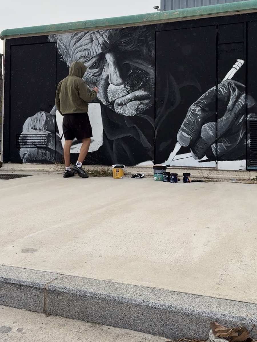 Dani painting a large black and white portrait mural